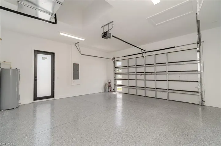 Garage featuring a garage door opener, water heater, and electric panel