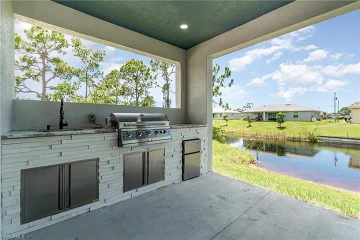 View of patio/lanai area with outdoor kitchen (full sink, grill and mini fridge)