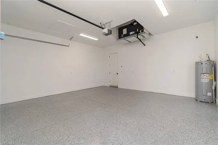 Garage featuring electric water heater and a garage door opener