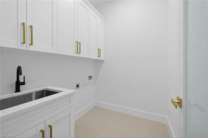 Washroom with hookup for an electric dryer, cabinet space, hookup for a washing machine, and baseboards