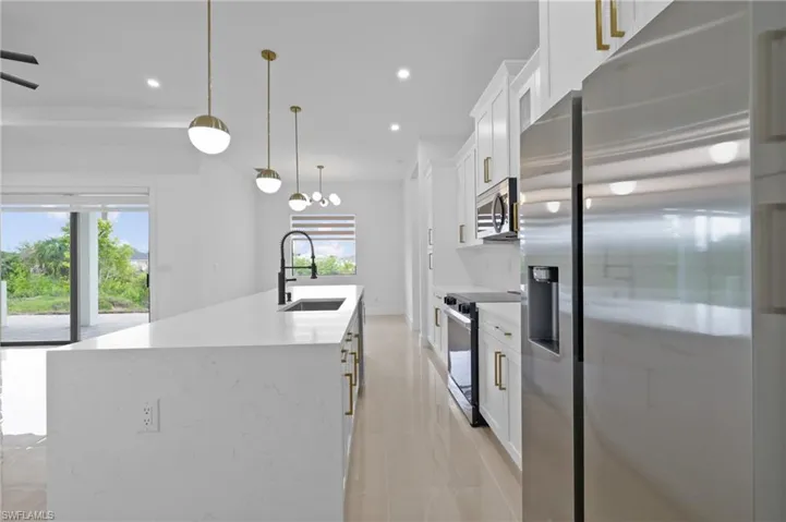 Kitchen with appliances with stainless steel finishes, a sink, plenty of natural light, white cabinets, and recessed lighting