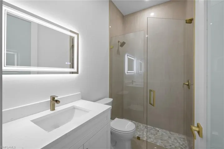 Bathroom featuring a stall shower, toilet, and vanity
