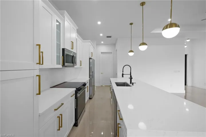 Kitchen with appliances with stainless steel finishes, a sink, white cabinets, recessed lighting, and glass insert cabinets