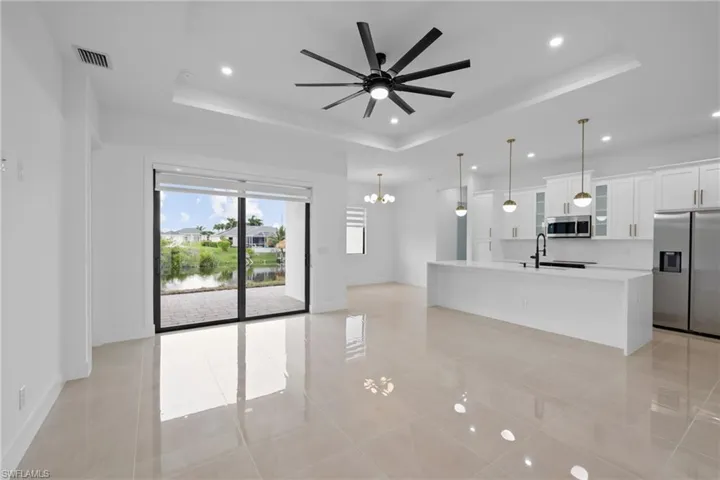 Kitchen featuring stainless steel appliances, a tray ceiling, recessed lighting, a chandelier, and ceiling fan