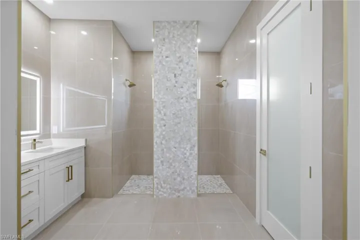 Full bathroom with walk in shower, vanity, tile patterned flooring, and tile walls