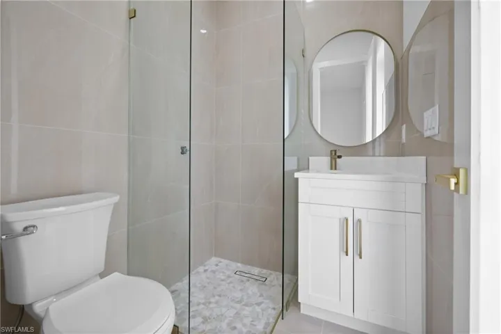 Full bath with toilet, tile walls, vanity, and a tile shower