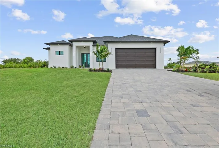Prairie-style house featuring decorative driveway, stucco siding, a front yard, and an attached garage