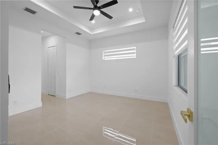 Empty room with ceiling fan, recessed lighting, a raised ceiling, and baseboards