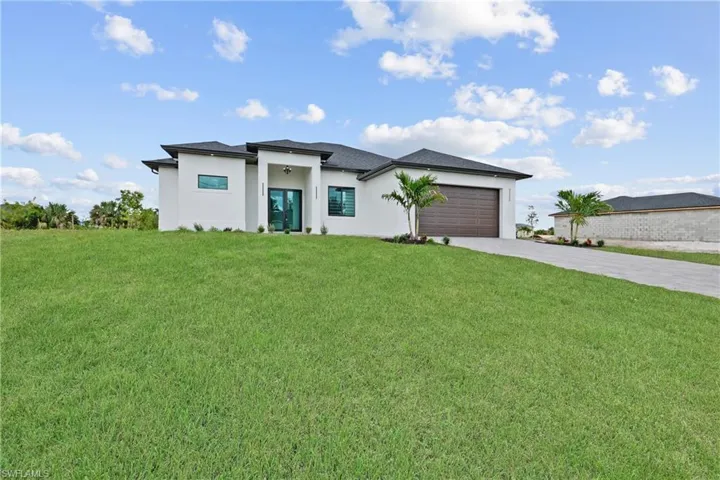 Prairie-style house featuring driveway, stucco siding, an attached garage, and a front lawn