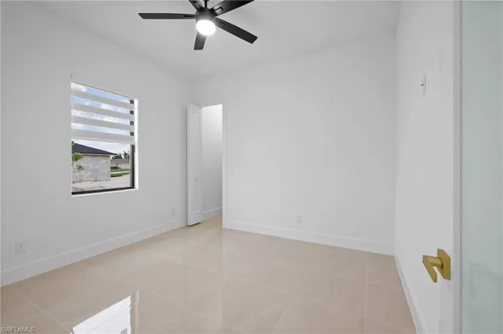 Unfurnished room featuring ceiling fan, baseboards, and light tile patterned flooring