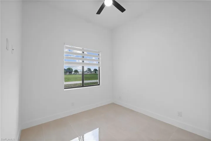 Spare room featuring ceiling fan, baseboards, and light tile patterned floors