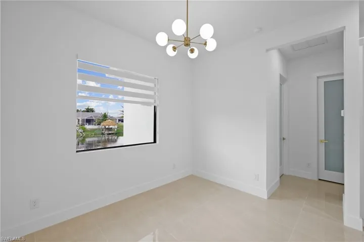 Empty room featuring baseboards, a chandelier, a smoke detector, and light tile patterned flooring