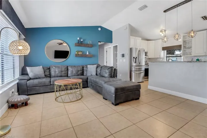 Living area featuring light tile patterned floors, a wealth of natural light, lofted ceiling, and visible vents