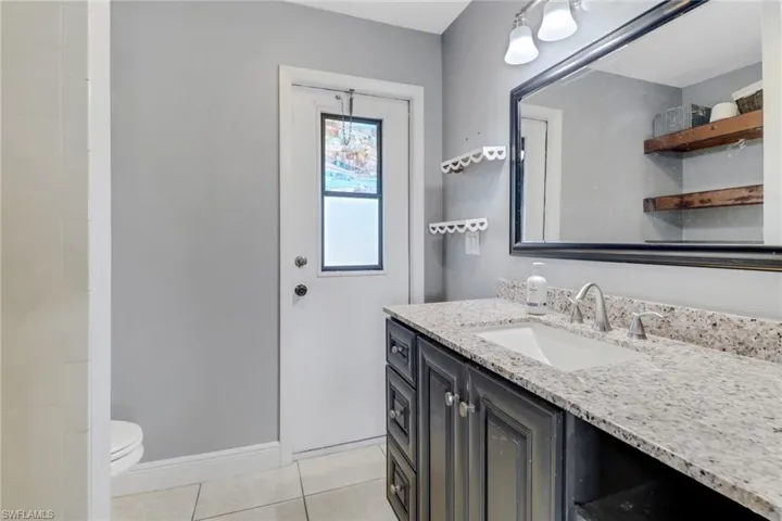 Bathroom featuring baseboards, vanity, toilet, and tile patterned floors