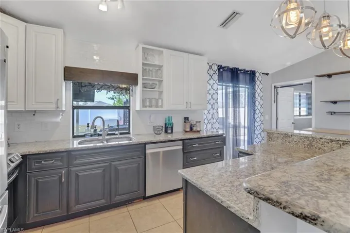 Kitchen with light countertops, white cabinetry, dishwasher, and a sink