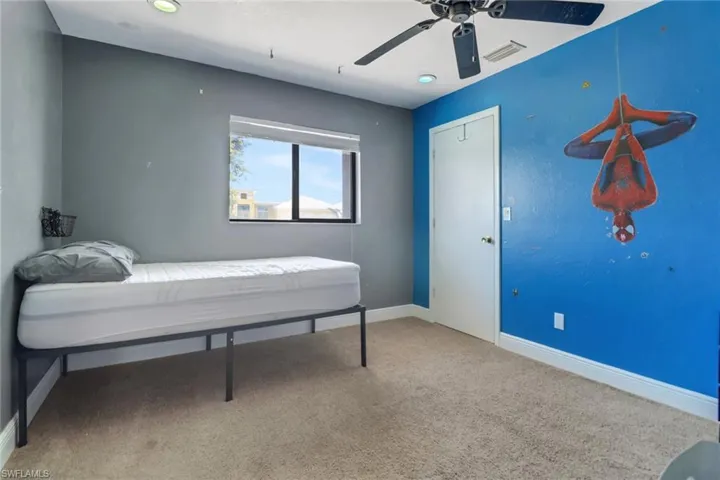 Carpeted bedroom with a ceiling fan, visible vents, and baseboards