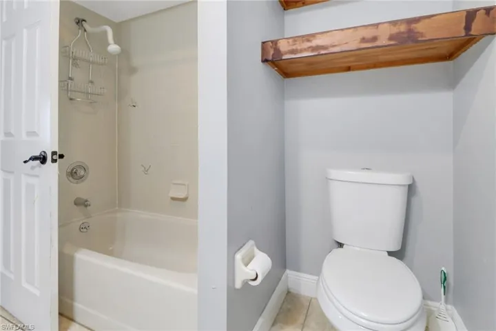 Bathroom featuring shower / washtub combination, tile patterned flooring, toilet, and baseboards