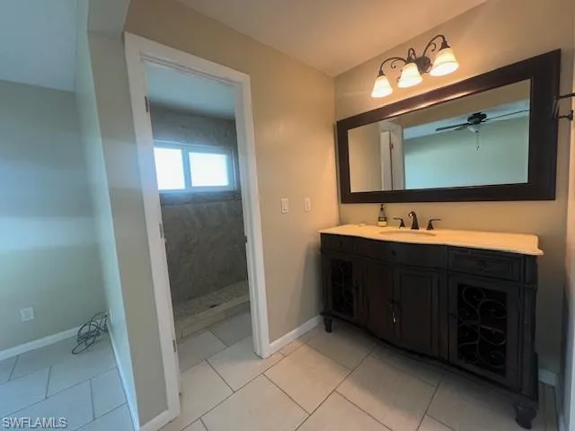 Bathroom with a ceiling fan, vanity, baseboards, and tile patterned floors
