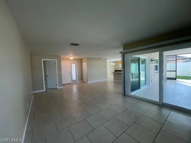 Spare room featuring light tile patterned floors, visible vents, and baseboards