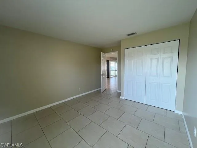 Unfurnished bedroom with a closet, visible vents, baseboards, and light tile patterned floors