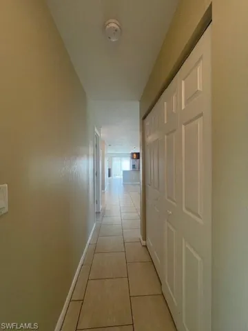 Hallway featuring light tile patterned floors and baseboards