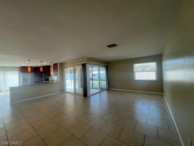 Unfurnished living room with light tile patterned floors, visible vents, and baseboards