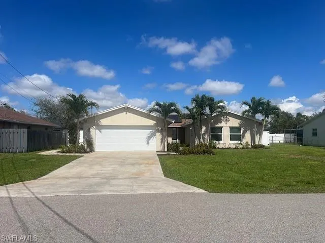 Ranch-style house with concrete driveway, a front lawn, an attached garage, and fence