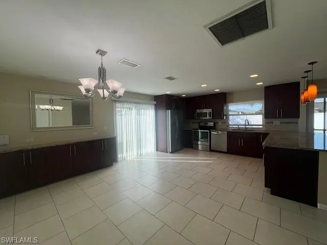 Kitchen with a notable chandelier, a sink, visible vents, appliances with stainless steel finishes, and pendant lighting