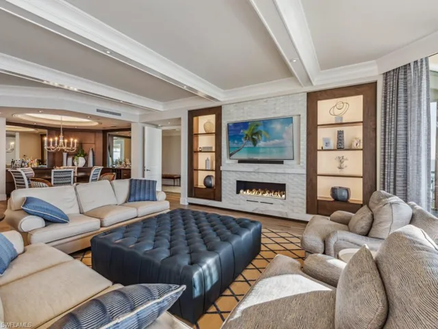 Living room with a fireplace, built in shelves, an inviting chandelier, and ornamental molding