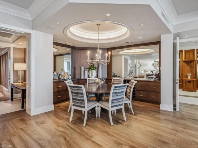 Dining space featuring a notable chandelier, a raised ceiling, crown molding, and light hardwood / wood-style flooring