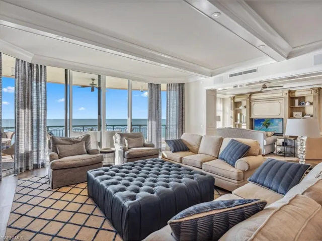 Living room featuring beam ceiling, light hardwood / wood-style flooring, expansive windows, crown molding, and a water view