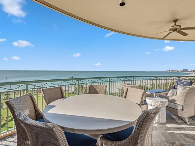 Balcony featuring a view of the beach, a water view, and ceiling fan