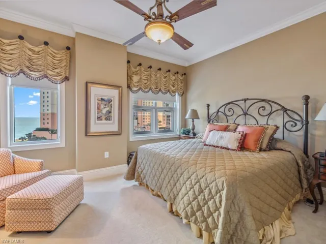 Carpeted bedroom featuring multiple windows, ceiling fan, crown molding, and a water view