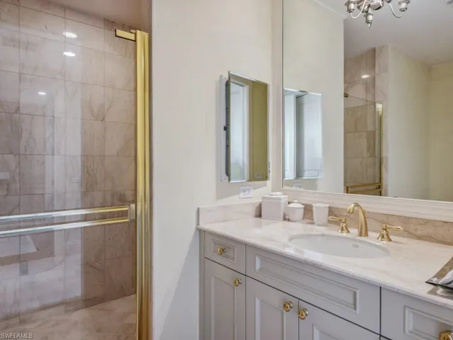 Bathroom featuring vanity, a shower with shower door, and a notable chandelier