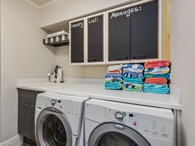 Laundry room featuring washer and clothes dryer, cabinets, ornamental molding, and sink