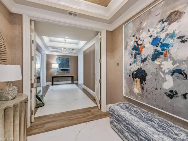 Hall featuring a tray ceiling, crown molding, and a notable chandelier