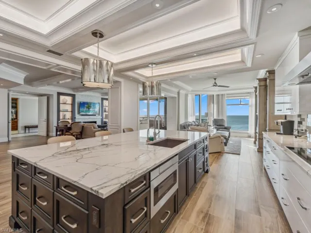 Kitchen with ceiling fan, sink, hanging light fixtures, crown molding, and white cabinets