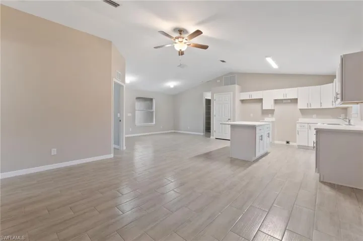 Kitchen featuring a kitchen island, light hardwood / wood-style flooring, vaulted ceiling, white cabinets, and ceiling fan