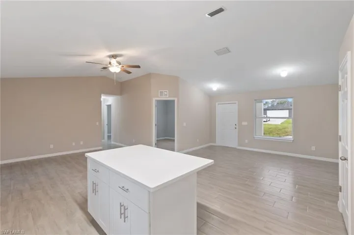 Kitchen featuring lofted ceiling, a kitchen island, white cabinets, and light hardwood / wood-style floors
