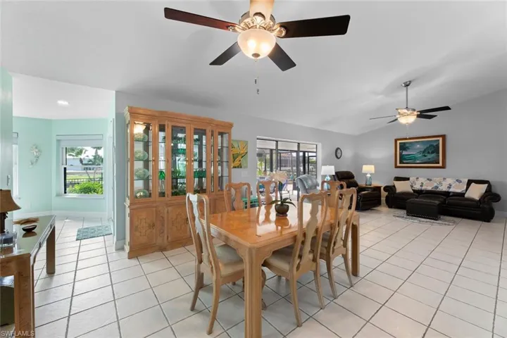Tiled dining space with ceiling fan and vaulted ceiling