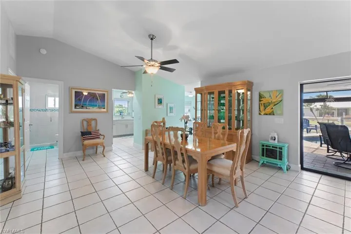 Dining space with vaulted ceiling, ceiling fan, and light tile floors