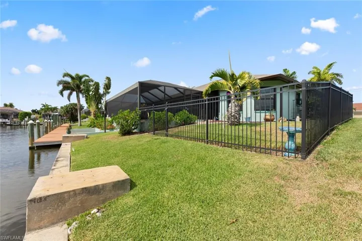 View of yard with glass enclosure, a water view, and a dock