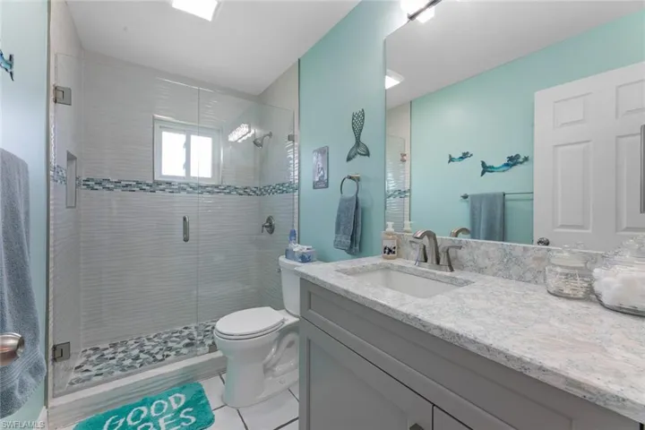 Bathroom with a shower with shower door, large vanity, and toilet