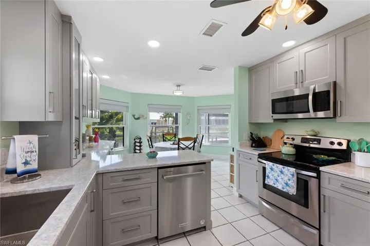 Kitchen featuring Quartz countertops with additional custom built space, ceiling fan, stainless steel appliances, gray cabinetry
