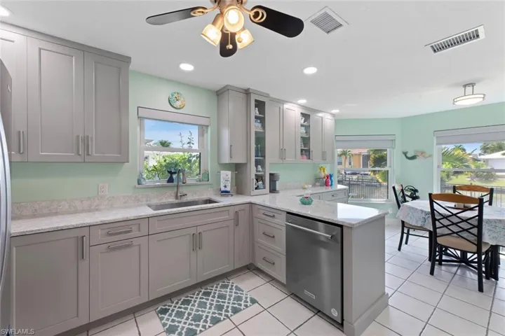 Newly remodeled Kitchen featuring Quartz peninsula, dishwasher, light tile floors