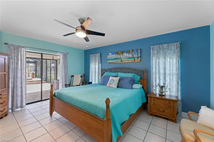Tiled bedroom with ceiling fan and slider access to lanai