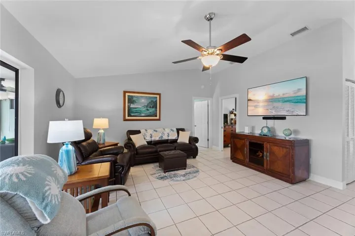 Tiled living room featuring ceiling fan and lofted ceiling