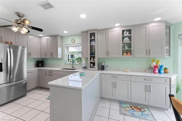 Newly remodeled kitchen boasts large rectangular extra deep sink, soft close Euro style Cabinetry, stainless steel appliance package, ceiling fan, and light tile floors