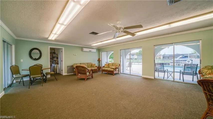 Living area featuring a ceiling fan, a textured ceiling, and crown molding
