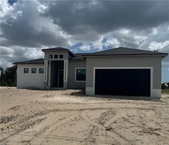 Prairie-style home with driveway, a garage, and stucco siding